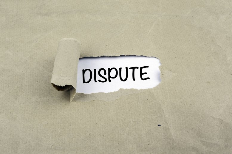 Image of a ripped piece of brown paper exposing a white background and the word "dispute" [Image by creator tumsasedgars from AdobeStock]