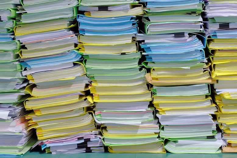 Photo of huge stacks of paper reports [Image by creator thewet from AdobeStock]