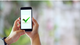 Man holding mobile phone displaying green checkmark [Image by creator  from insideARM]