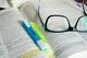 a pair of glasses lays on an open book with two highlighters, yellow and blue [Image by creator Hans from Pixabay]