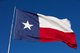 A large Texas flag flying against a bright blue sky [Image by creator 33ft from AdobeStock]